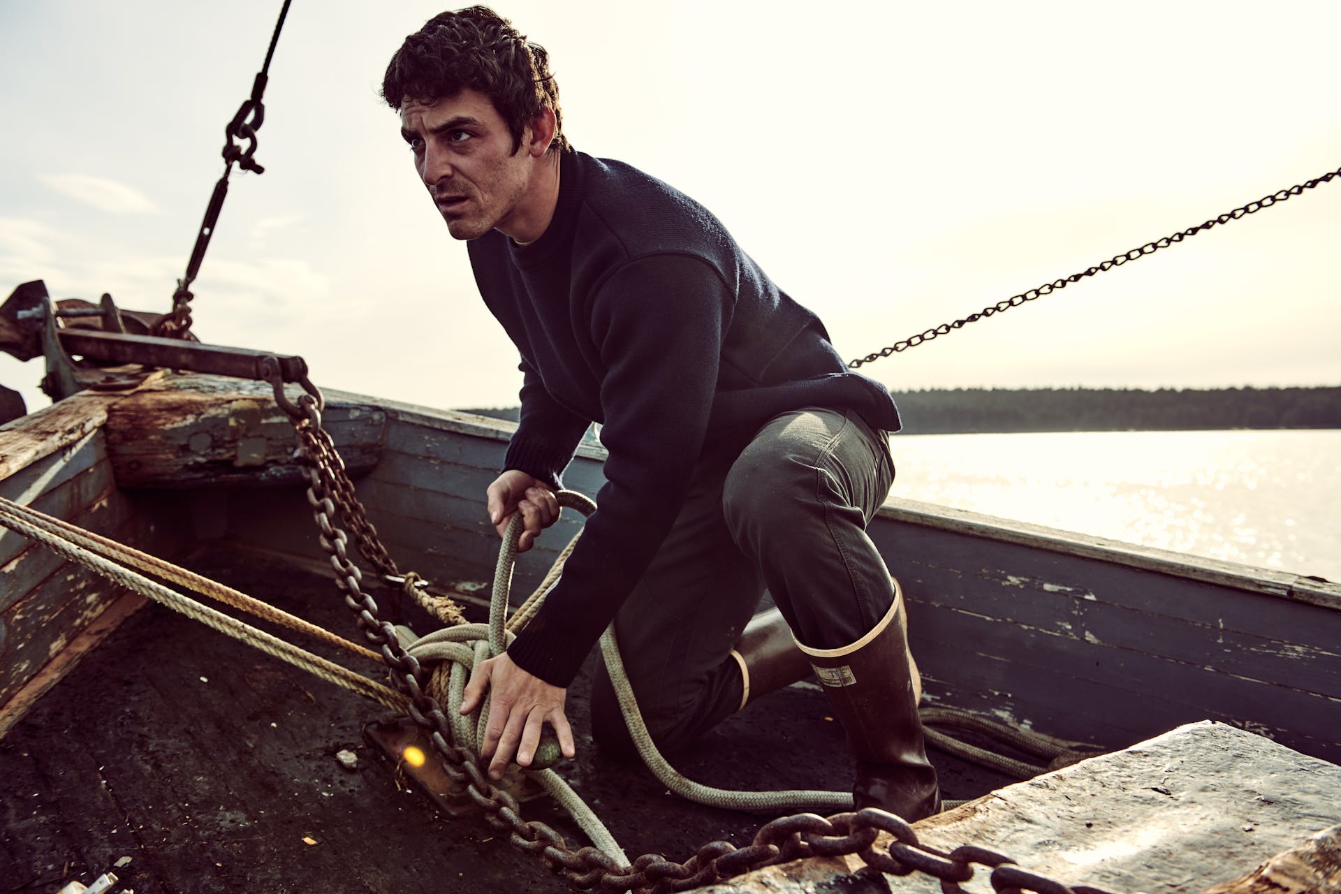 Sailor on a boat tying a knot on a cleat wearing a Filson Crewneck Guide Sweater