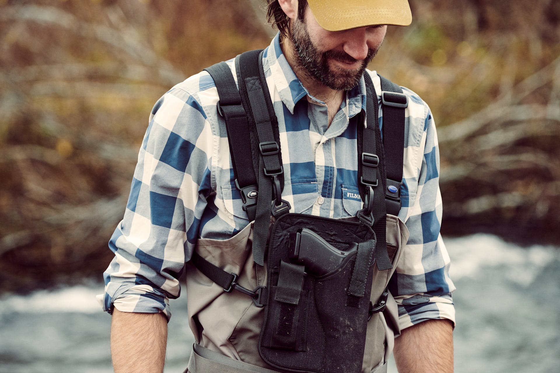 Man wearing Filson Twin Lakes Sports Shirt in charcoal/teal/cream and shooting vest looking down and grinning