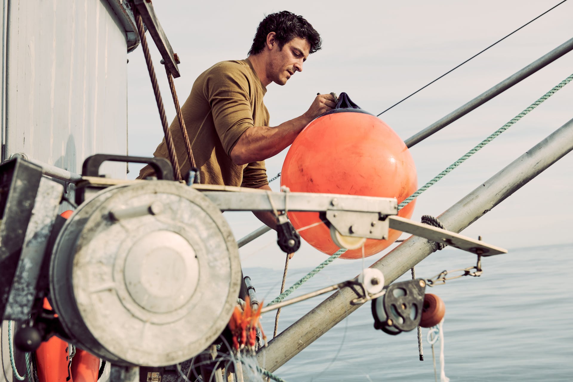 Fisherman carrying a buoy over a boat wearing a Filson 280G Merino Long Sleeve Crew shirt