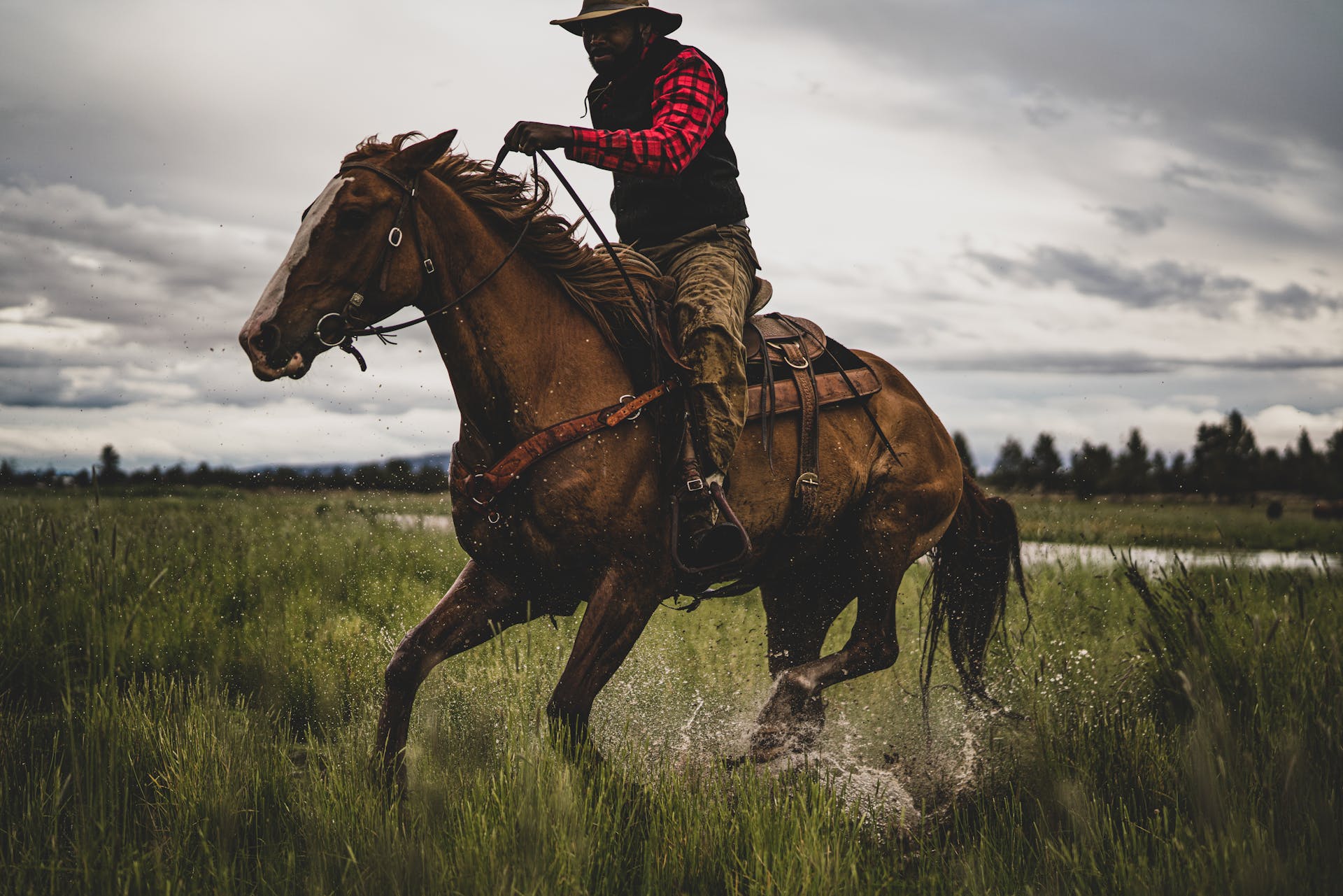 Man wearing Filson Mackinaw Wool Vest in charcoal riding a horse through wetlands