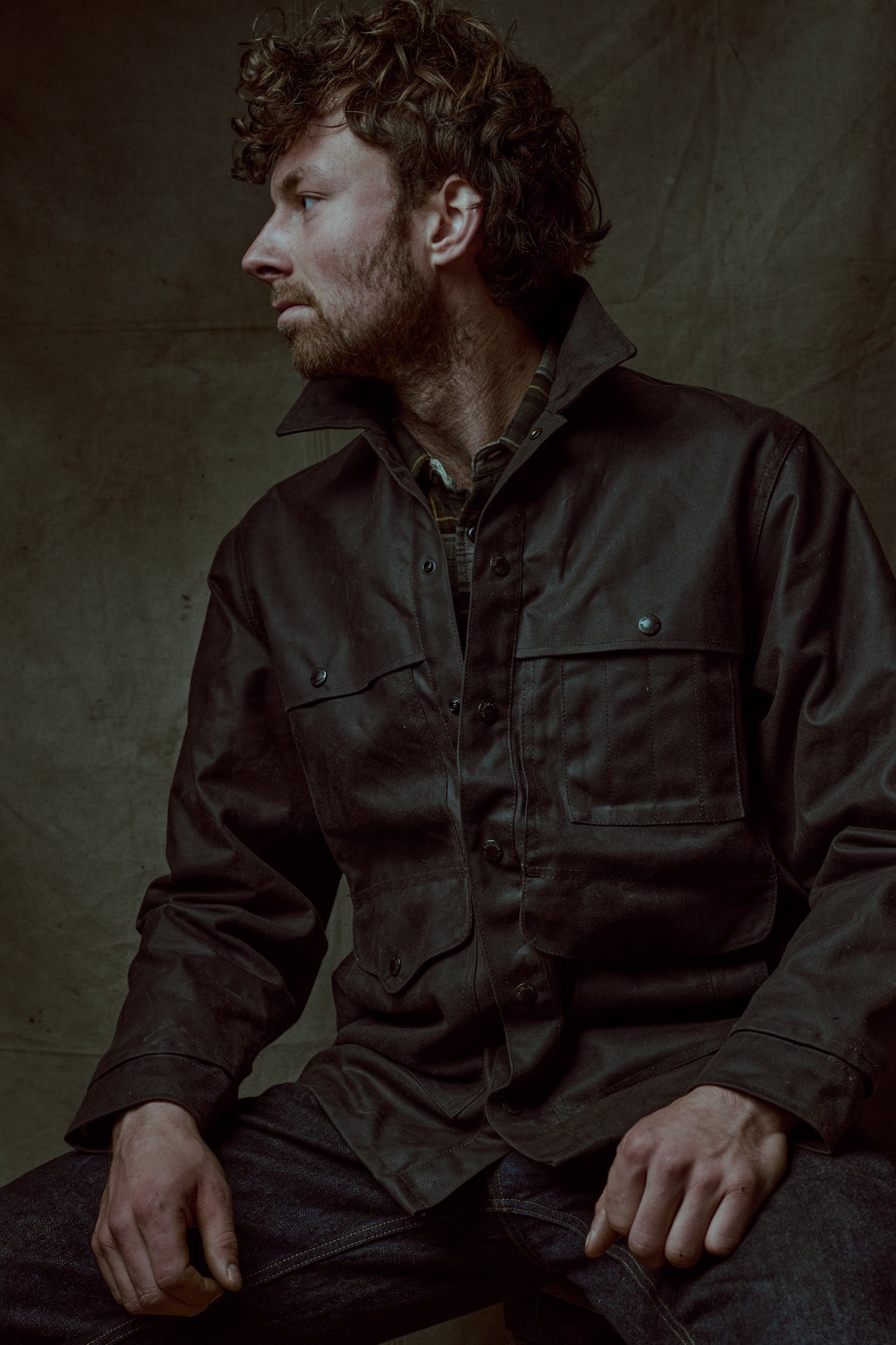 Sailor sitting in a dim room wearing a Filson Lined Tin Cloth Cruiser Jacket
