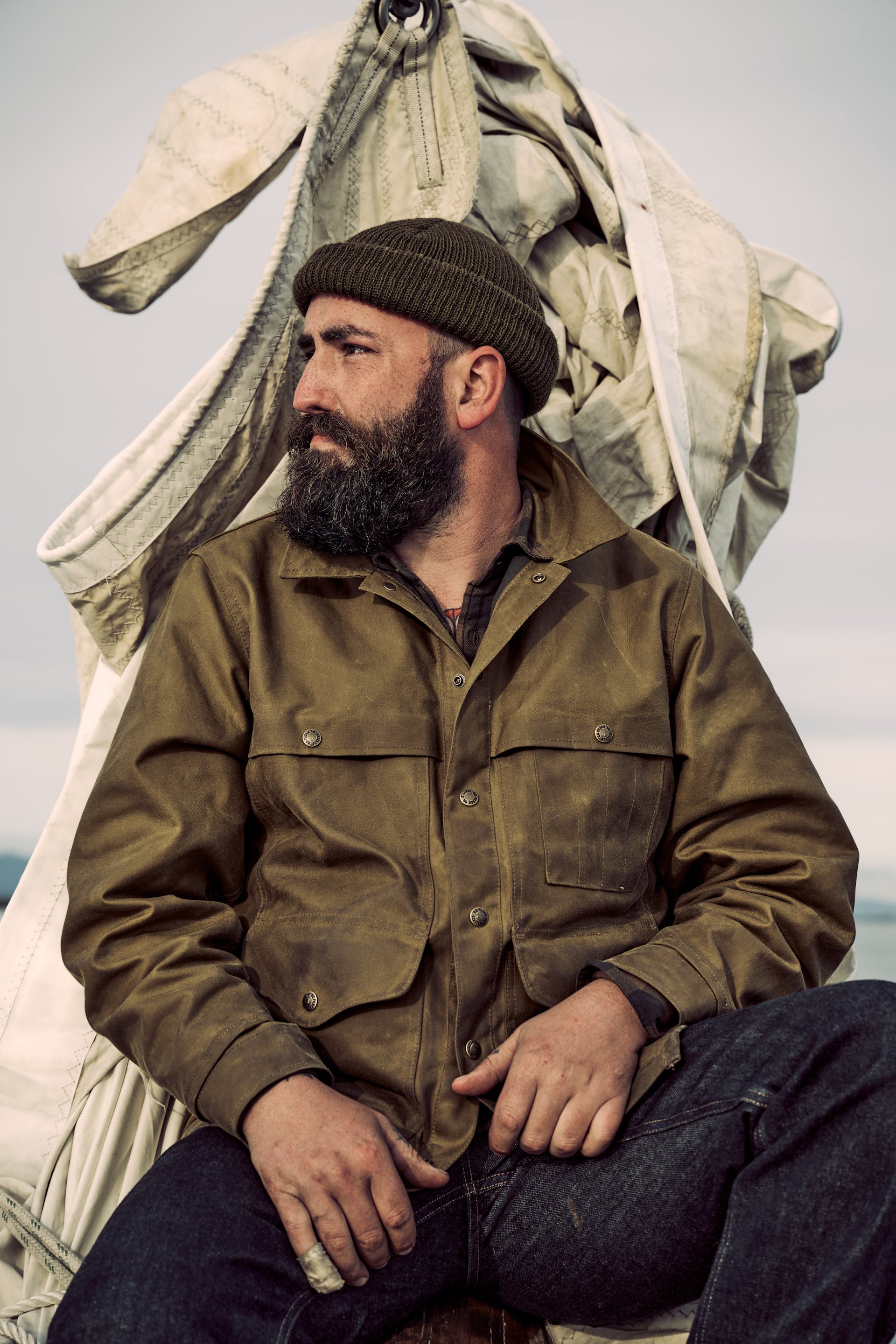 Sailor sitting on a boat wearing a Filson Lined Tin Cloth Cruiser Jacket