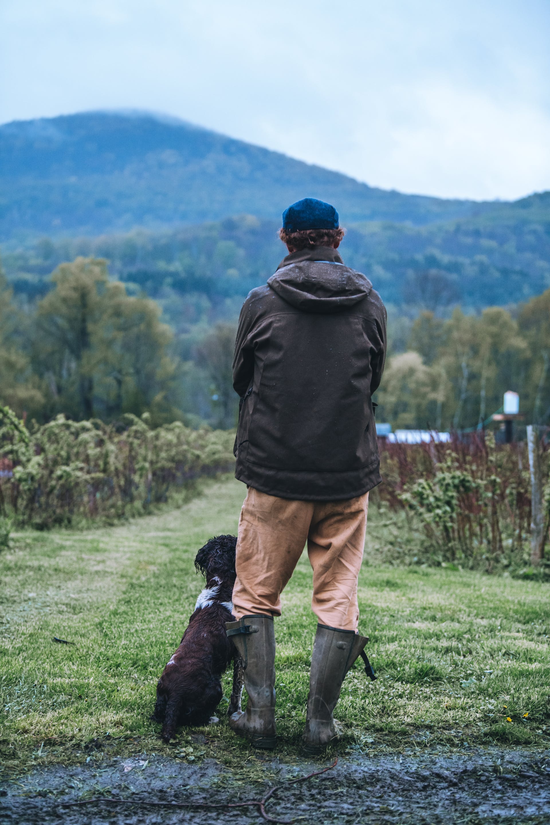 Man standing with dog in a field wearing a Filson 3-Layer Field Jacket