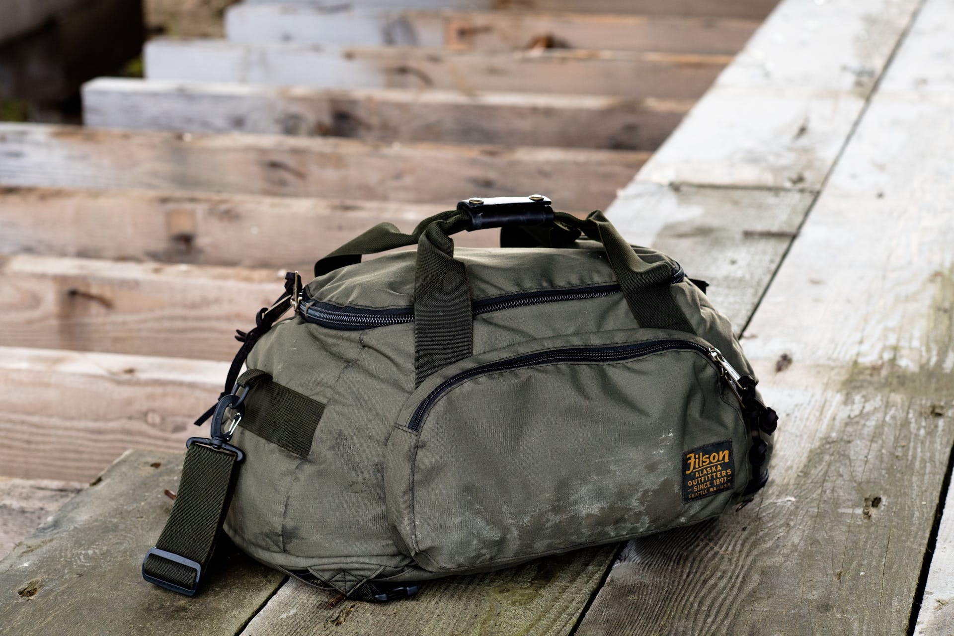 Filson Duffle Pack in otter green resting on wooden plank