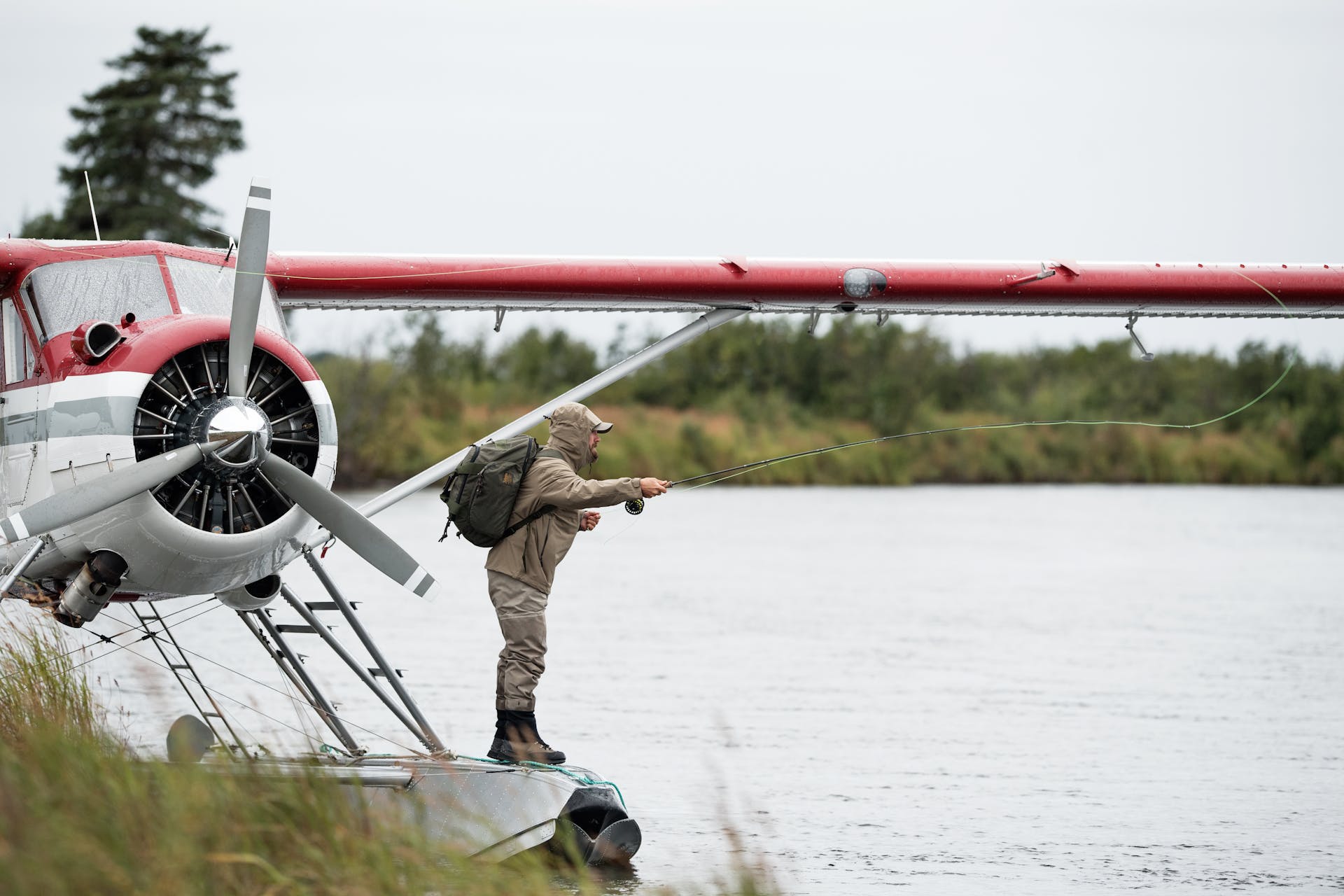 Man wearing Filson Duffle Pack in otter green fishing from a seaplane