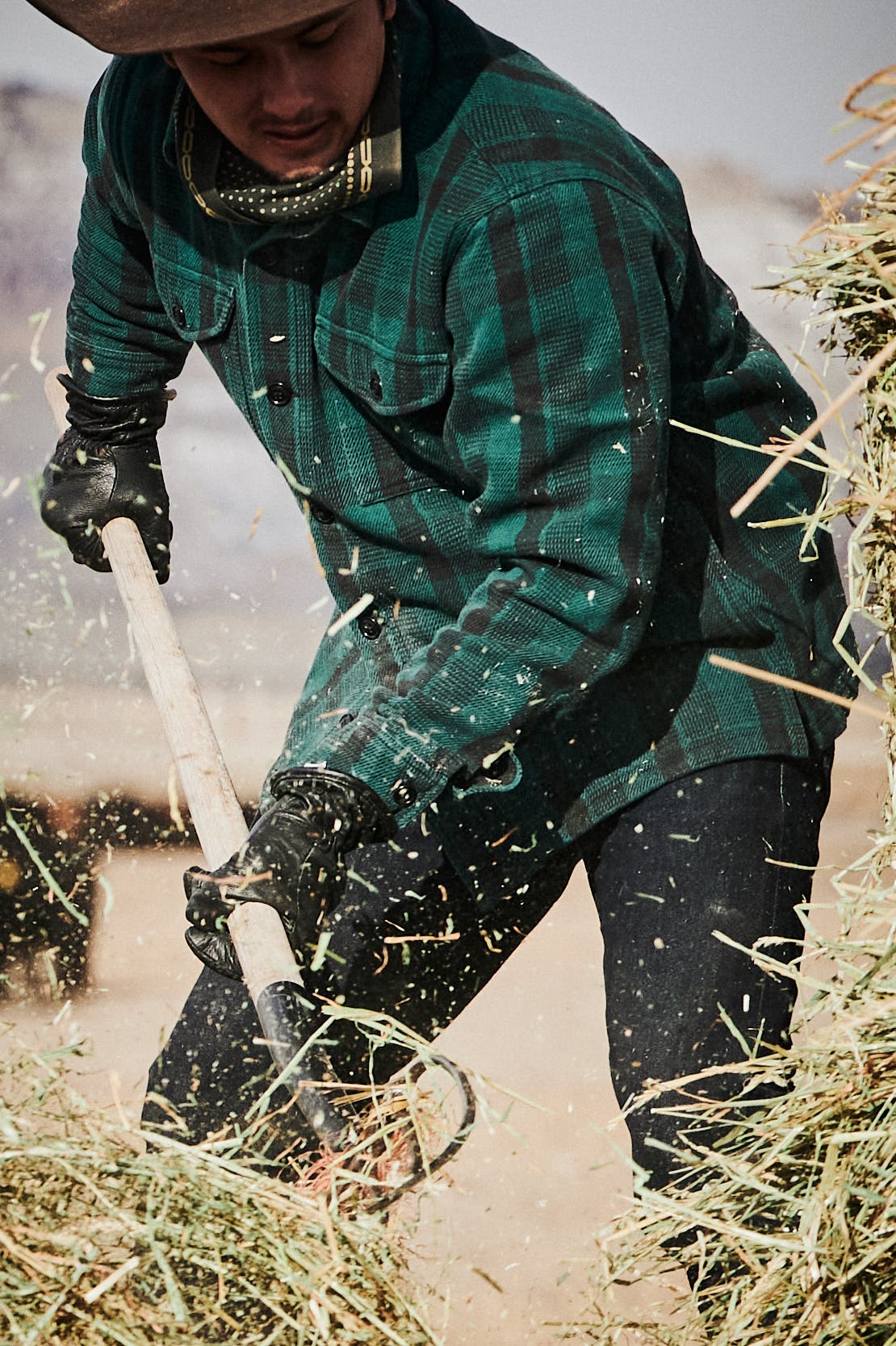 Man shoveling hay on a ranch wearing a Filson Deer Island Jac-Shirt