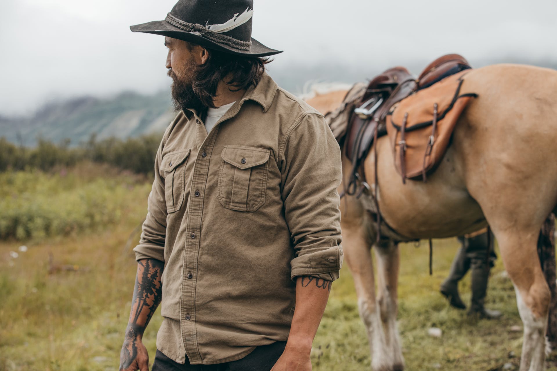 Man standing in a field in front of a horse wearing a Filson Moleskin Seattle Shirt