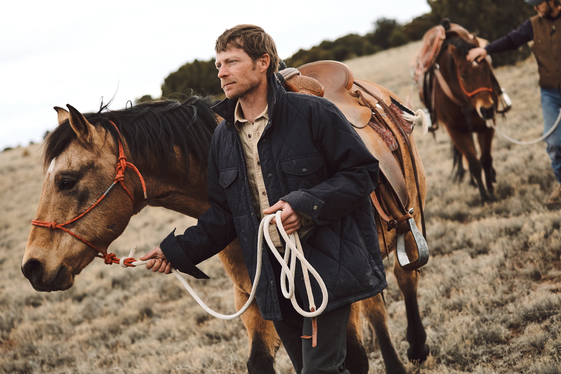 Man wearing Filson Hyder Quilted Jac Shirt in faded navy leading his horse through a field