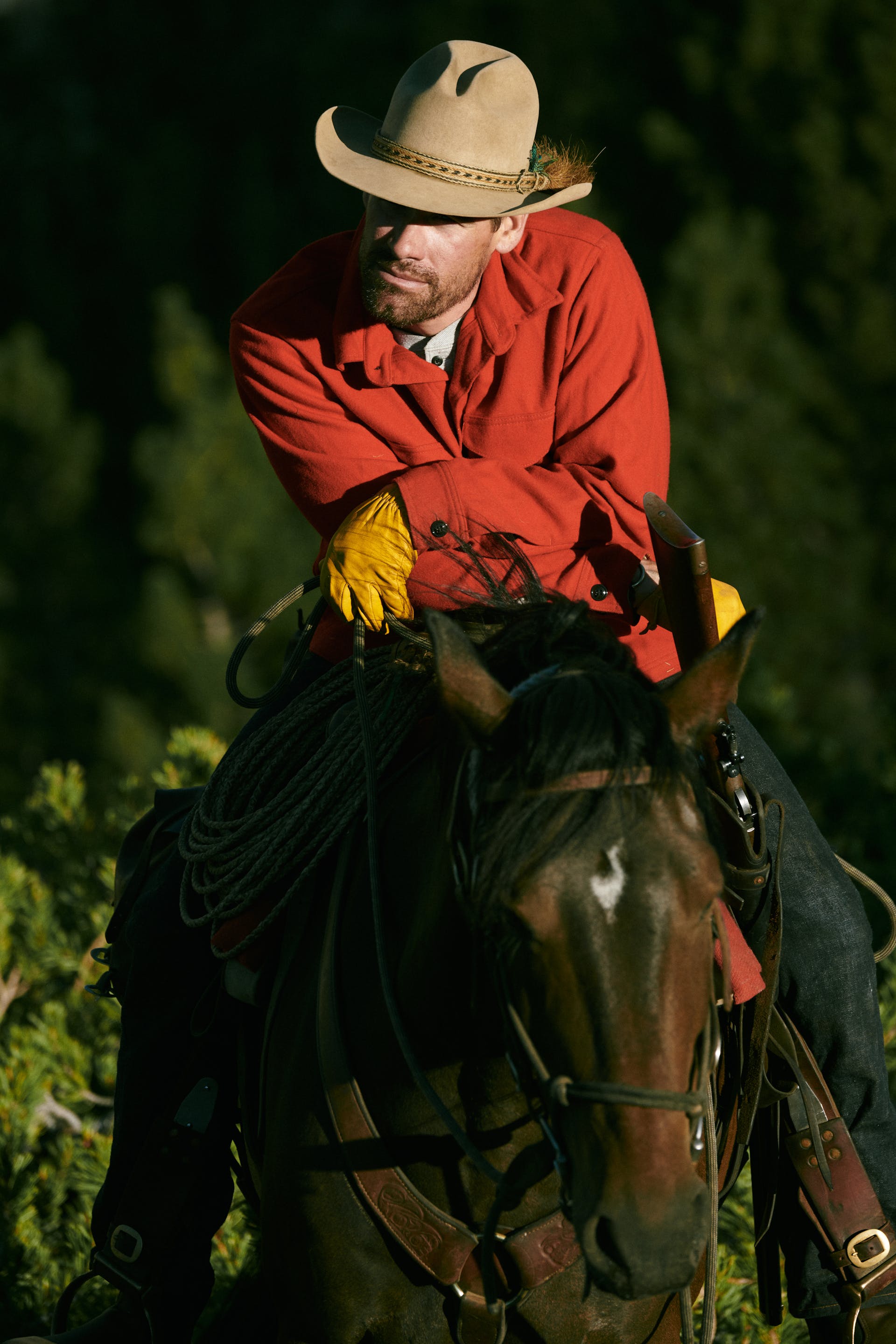 Man wearing Filson Jac-Shirt in scarlet red resting on his forearms while sitting on a horse