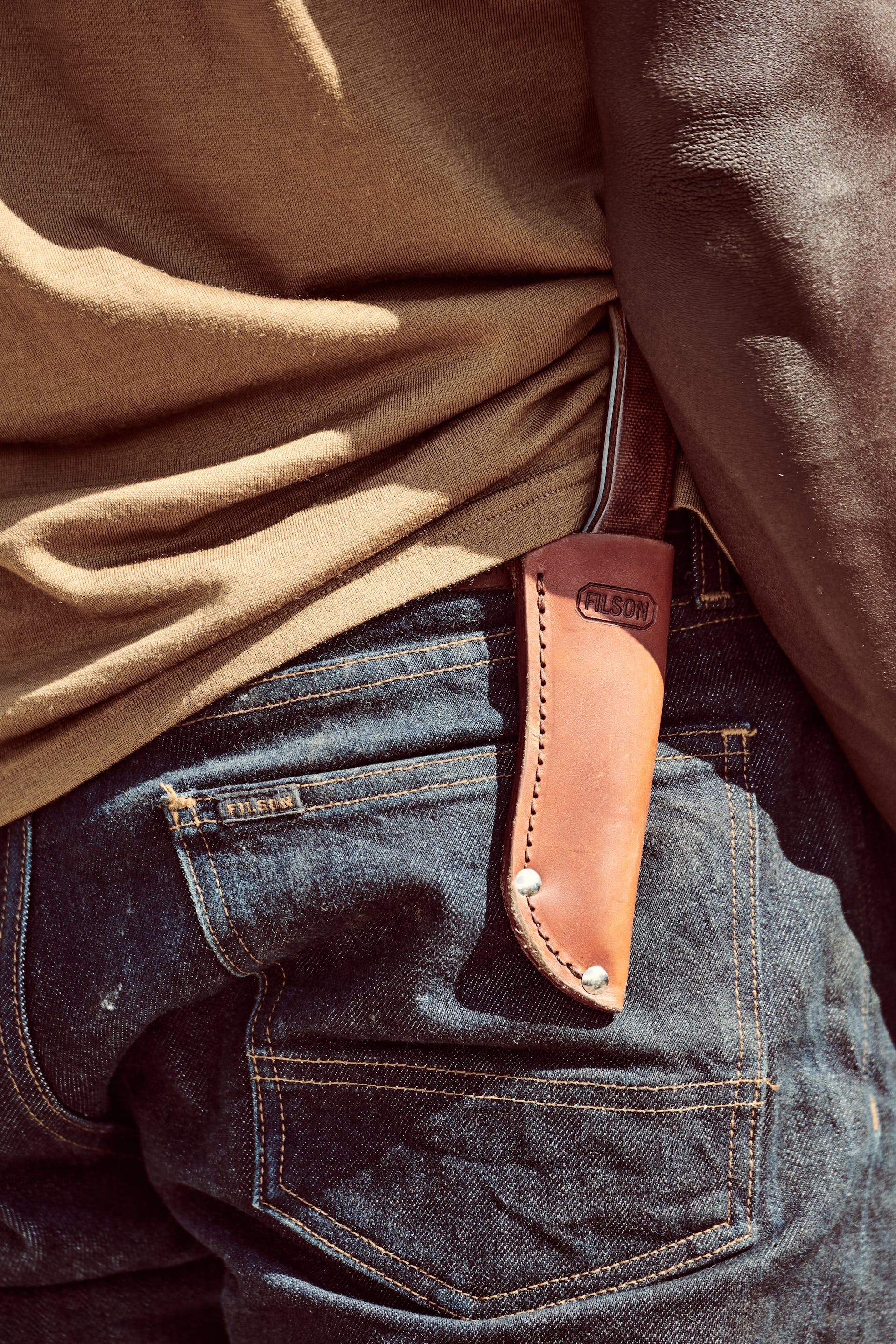 Man wearing denim with a Filson Bird & Trout knife in a sheath on his belt