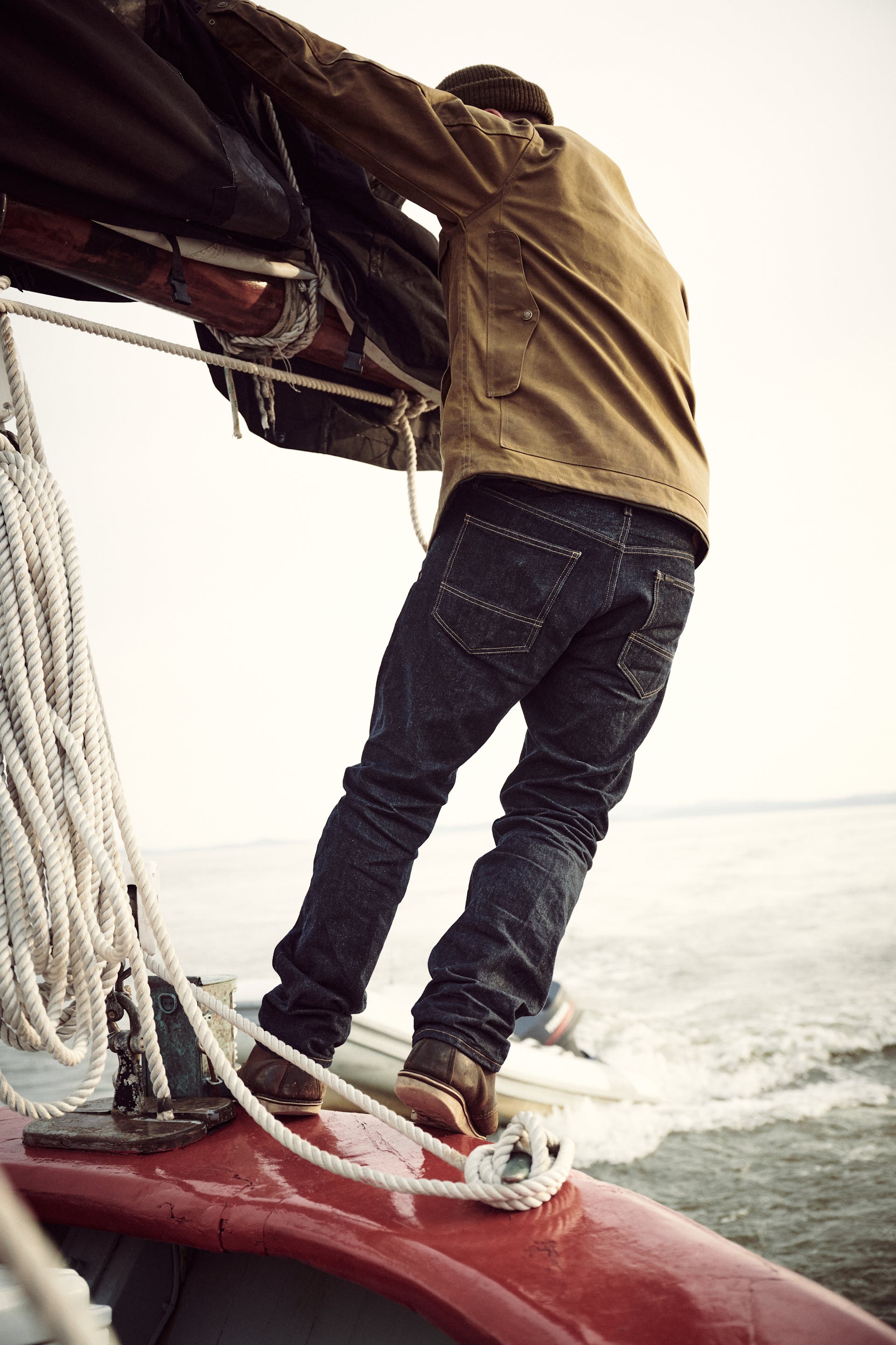 Sailor tying rope onto a mast wearing a Filson Lined Tin Cloth Cruiser Jacket