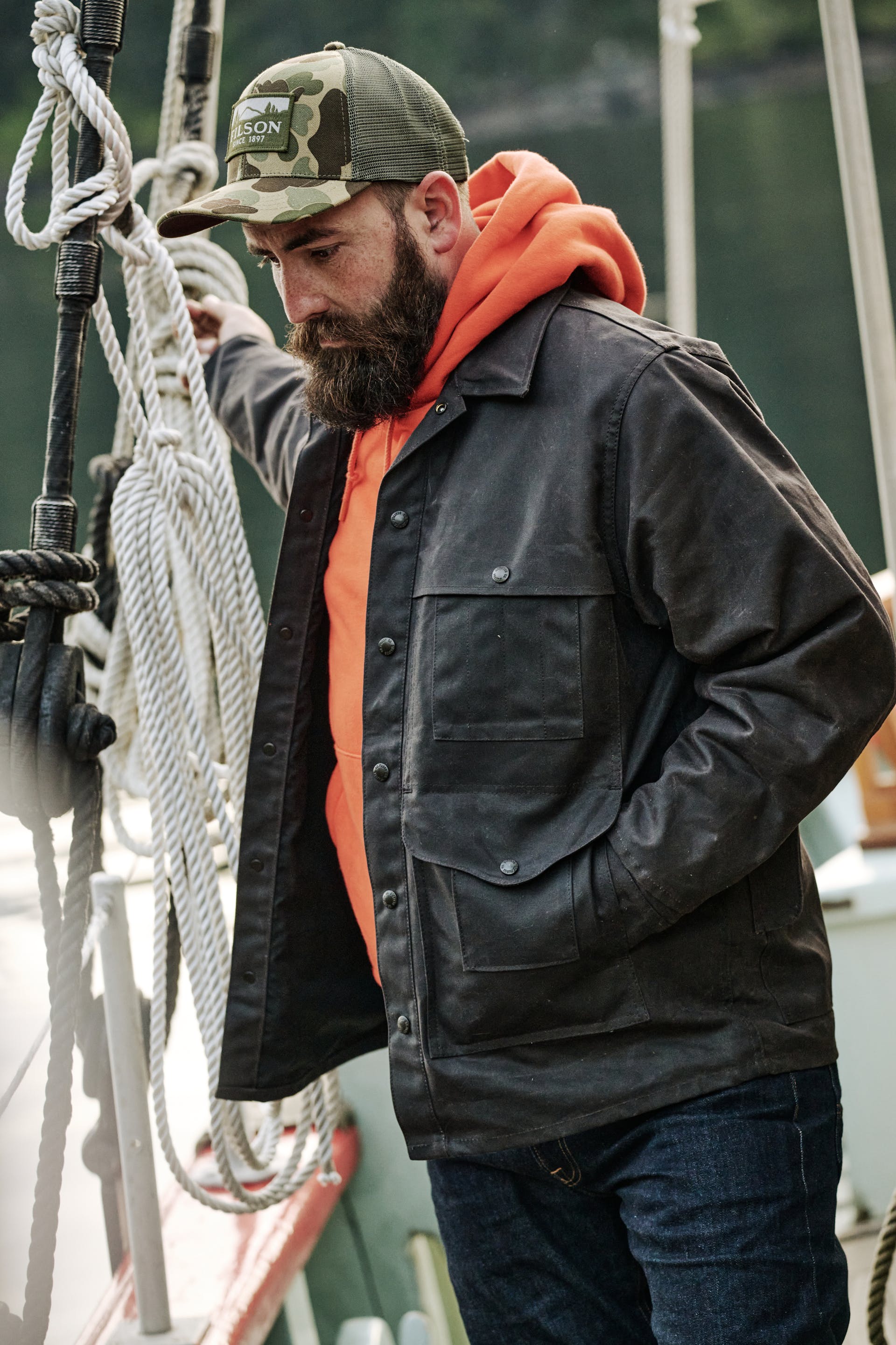 Man walking on a boat wearing a Filson Lined Tin Cloth Cruiser Jacket