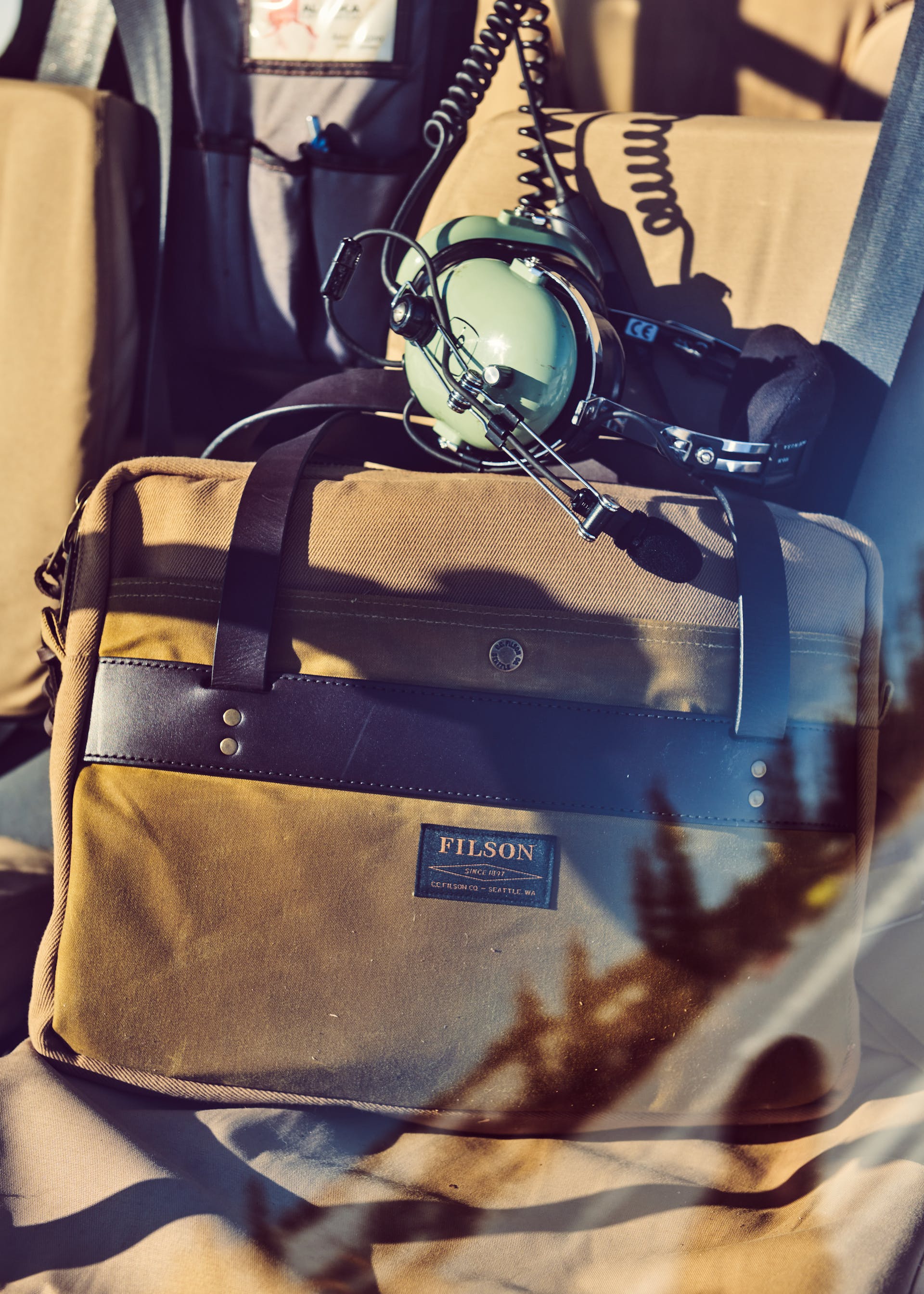 Filson Rugged Twill Compact Briefcase in sportsman tan resting on a helicopter seat