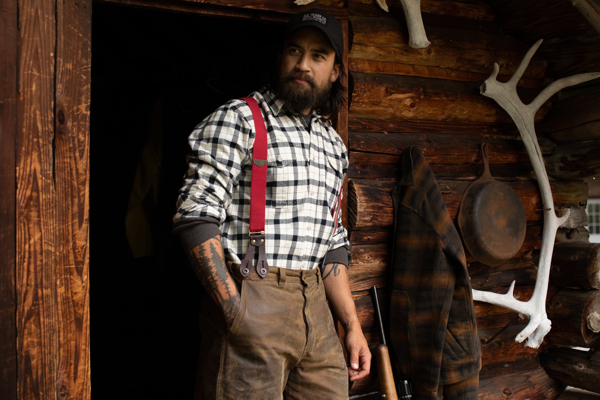 Man standing on a front porch of a cabin wearing a Filson Alaskan Guide Shirt