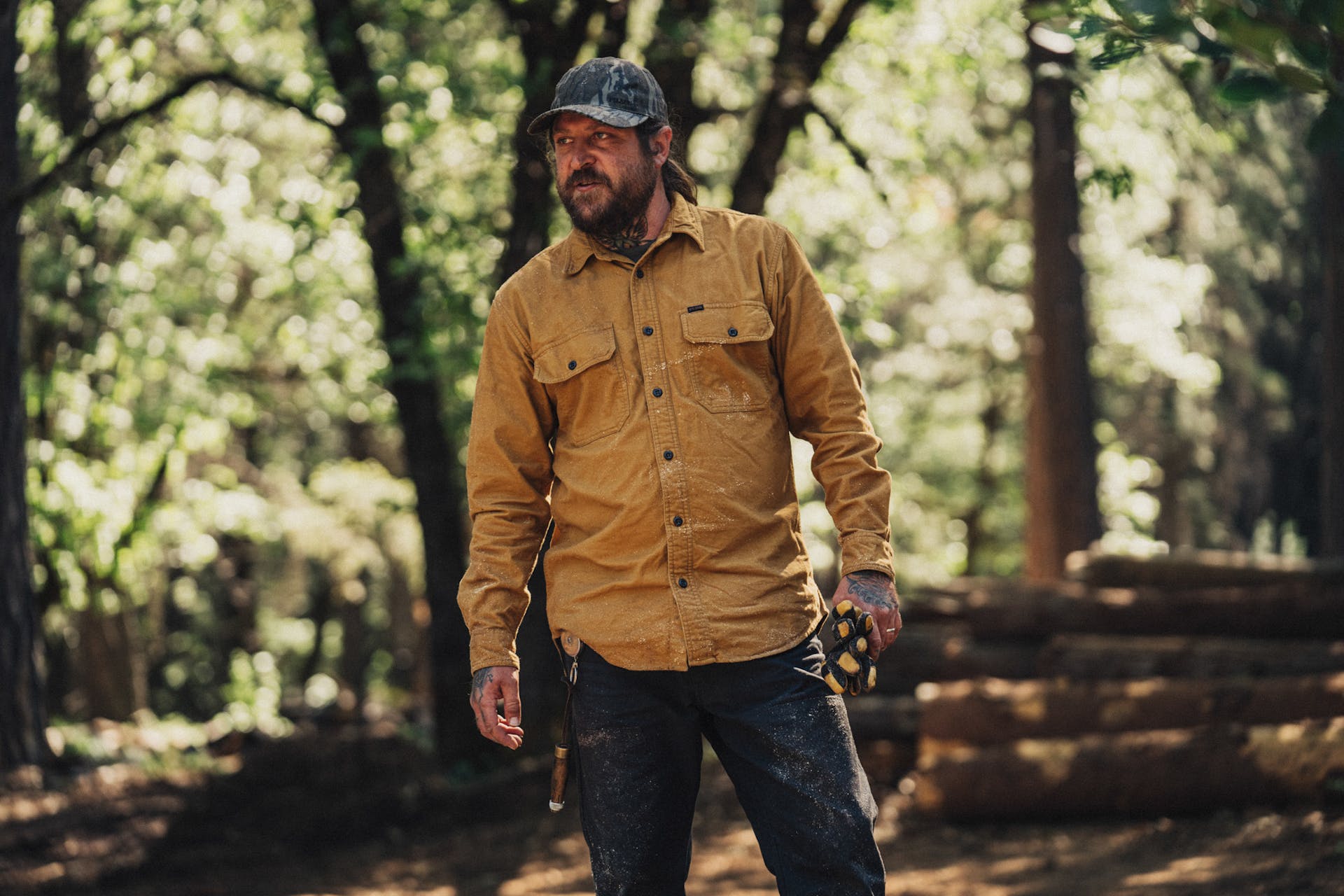 Logger standing in front of logs after working wearing a Filson Field Flannel Shirt
